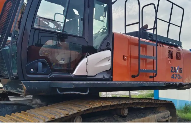 A close-up view of the operator's cabin and side paneling of an orange Hitachi Zaxis 470H heavy-duty excavator.