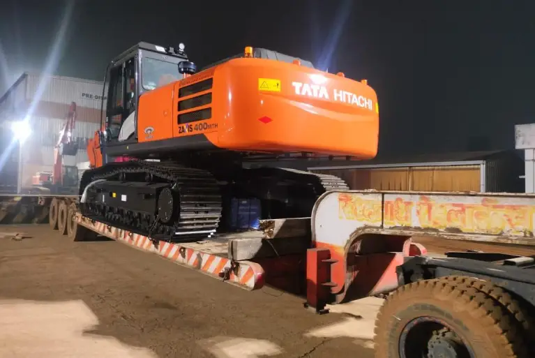 Tata Hitachi Zaxis 400 MTH hydraulic excavator being transported on a lowbed trailer at night.