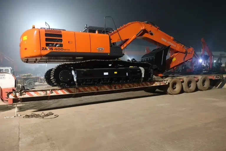 Full side view of a Tata Hitachi Zaxis 400 MTH Quarry excavator being transported on a heavy-duty low-bed trailer at night.